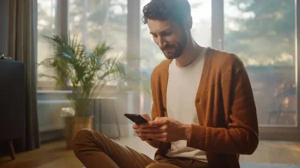 Mies Käyttää Älypuhelinta Kotona Tekee Etätyötä Komea Hymyilevä Mies Istuu — kuvapankkivalokuva