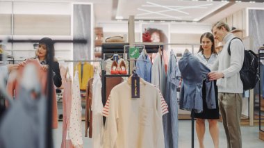 Giyim mağazasından alışveriş yapan, perakende satış yapan ve danışmanlık hizmeti veren genç çiftler. Moda Mağazasında Çeşitli İnsanlar, Şık Kıyafetler Seçmek, Sürdürülebilir Tasarımlı Renkli Markalar