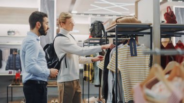 Yakışıklı Erkek Müşteri Alışveriş Mağazası, Perakende Satış Asistanı Danışmanlığa Yardım Ediyor. Moda Mağazasında Çeşitli İnsanlar, Şık Kıyafetler Seçmek, Sürdürülebilir Tasarımlı Renkli Markalar
