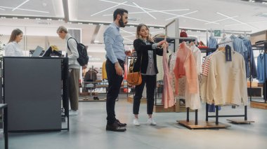 Giyim Mağazasından Güzel Kadın Müşteri Alışverişi, Perakende Satış Ortaklığı Danışmanlığa Yardım Ediyor. Moda Mağazasında Çeşitli İnsanlar, Şık Kıyafetler Seçmek, Sürdürülebilir Tasarımlı Renkli Markalar