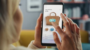 Güzel Beyaz Kadın, New Collection 'dan El Çantası Seçmek ve Almak İçin İnternetten Smartphone Kullanıyor. İnternette Sörf Yapan ve Oturma Odasında Kanepede Yatan Kadın.