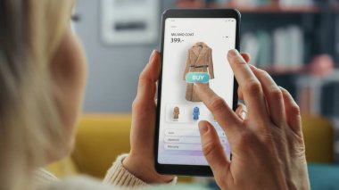 Güzel Beyaz Kadın, New Collection 'dan Elbise Seçip Almak İçin İnternet Mağazası ile Akıllı Telefon Kullanıyor. İnternette Sörf Yapan ve Oturma Odasında Kanepede Yatan Kadın.