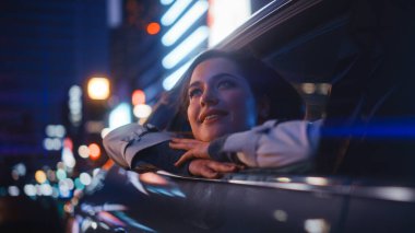 Heyecanlı Genç Kadın Bir Arabanın Arka Koltuğunda Oturuyor, Gece Evden Eve Gidiyor. Pencereden Neon tabelalarıyla Şehir Caddesinin ne kadar güzel olduğuna bakıyorum..