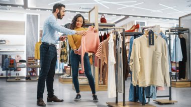 Genç Bayan Müşteri Alışverişi Giyim Mağazasından, Perakende Satış Ortaklığı Danışmanlığa Yardım Ediyor. Moda Mağazasında Çeşitli İnsanlar, Şık Kıyafetler Seçmek, Sürdürülebilir Tasarımlı Renkli Markalar