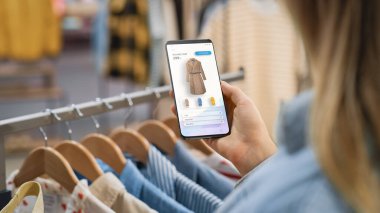 Giysi Mağazası: Smartphone 'u Çevrimiçi Moda Mağazası Kullanıcı Arayüzü ile Son Fiyatı Markalı Ceket ile Çek Price' a Kullanan Kadın. Mobil Aygıtın Omuz Çekiminin Üstünü Kapat.