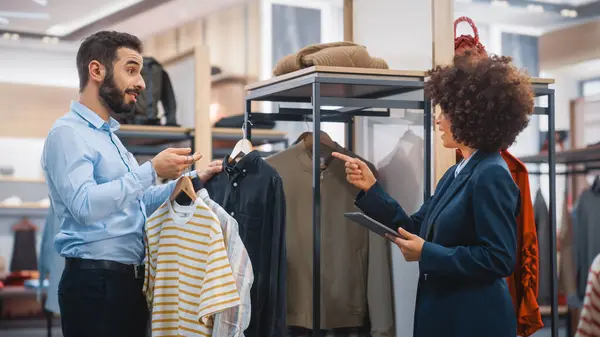 Clothing Store: Businesswoman Uses Tablet Computer, Talks to Visual Merchandising Specialist, Collaborate To Create Stylish Collection. Small Business Fashion Shop Sales Manager Talks to Designer.