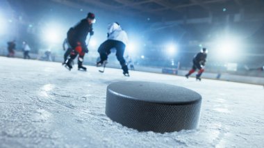 Buz hokeyi sahasında 3 boyutlu hokey diskine odaklanarak yakın çekim. Arka planda Puck 'ı almaya çalışan farklı takımlardan profesyonel oyuncular vardı. Hollanda Açı Vuruşu.