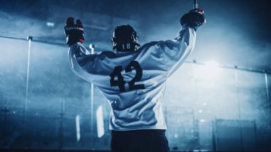 Buz Hokeyi Oyunu: Profesyonel Oyuncu Rink 'te Zaferi Kutluyor, Kollarını Yükseltiyor. Neşeli Genç Sporcu, Gayret ve Kararlılıkla Şampiyon Oldu.