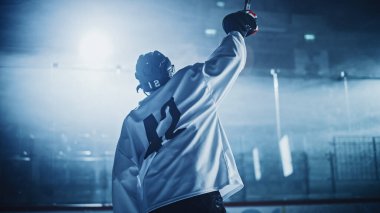 Buz Hokeyi Oyunu: Profesyonel Oyuncu Rink 'te Zaferi Kutluyor, Kollarını Yükseltiyor. Neşeli Genç Sporcu, Gayret ve Kararlılıkla Şampiyon Oldu.