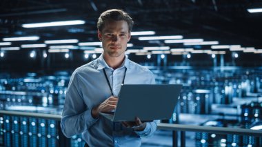 Data Center 'da dizüstü bilgisayar kullanan yakışıklı bir bilişim uzmanı. Başarılı İşadamı ve e-İş Girişimcisi Sunucu Çiftliği Bulut Hesaplama Tesisi.