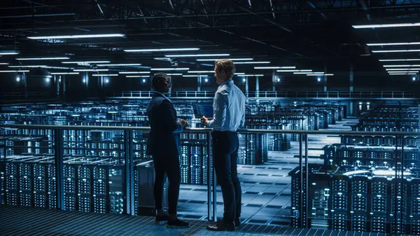 stock image Data Center Male IT Specialist and Female e-Business Enrepreneur Talk, Use Laptop. Two Information Technology Professionals on Bridge Overlooking Big Cloud Computing Server Farm.