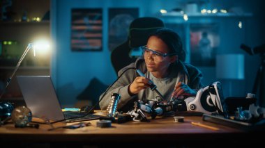 Genç Genç Çok Irklı Öğrenci Elektronik ve Lehim Kabloları ve Bilimsel Hobi Robotları Projesinde Devre Tahtaları okuyor. Kız, odasında bir robot üzerinde çalışıyor. Eğitim Konsepti.