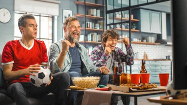 Home Three Joyful Soccer hayranları TV 'de bir kanepede oturmuş, Spor Takımı Şampiyonluğu' nu kazandığında zaferi kutluyorlar. En Sevilen Futbol Kulübü Oyunu 'nda Arkadaşlar Grubu Tezahürat Eder.