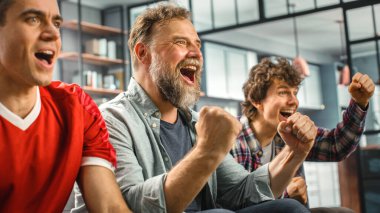 Home Three Joyful Soccer hayranları TV 'de bir kanepede oturmuş, Spor Takımı Şampiyonluğu' nu kazandığında zaferi kutluyorlar. En Sevilen Futbol Kulübü Oyunu 'nda Arkadaşlar Grubu Tezahürat Eder.