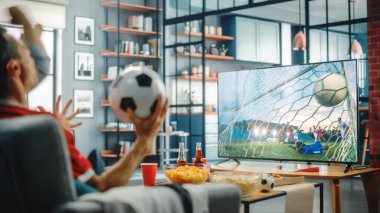 Home Soccer Fans TV 'de bir kanepede oturan futbol maçı, Favori Spor Takımı için tezahürat şampiyonluğu. Ekranda Profesyonel Futbol Kulübü Oyunu var. Omzunun üstünden.
