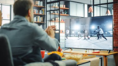 Ev Buzu Hokey Hayranları TV 'de Kanepe İzleme Maçı' nda, Favori Spor Takımı Şampiyonayı Kazanınca Tezahürat. Ekranda Dünya Kupası Sırasındaki Profesyonel Oyuncular gösteriliyor. Omzunun üstünden.