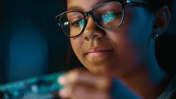 一个可爱的年轻少女多种族黑人女孩的特写正在研究一个小的印刷电路板对象 年轻女性戴眼镜与学校科学项目的研究 — 图库照片