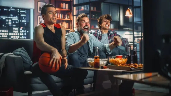Hjemme Tre Glade Basketballfans Som Sitter Sofa Spill Feire Seier – stockfoto