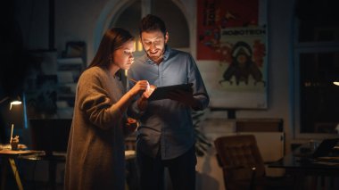 Mutlu ve Başarılı Çalışanlar, Çatı katında Yaratıcı Ajans 'taki Tablet Bilgisayarda İşle İlgili Projeleri Tartışıyor. Bitkiler, Posterler ve Yuvarlak Pencereli Karanlık Yenilenmiş Alan.