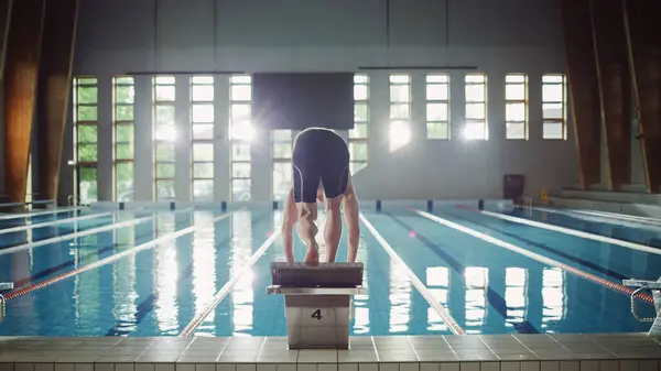 Muscular Mature Male Swimmer Standing on a Starting Block and Prepairing to Jump into Swimming Pool. Healthy Professional Athlete Training for the Championship. Shot with Sunflare