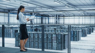 Veri Merkezi Mühendisi Dizüstü bilgisayar kullanıyor. Siber Güvenlik için Veri Koruma Ağı ile çalışan çok ırklı kadın sistem yöneticisiyle Sunucu Çiftliği Bulutu Bilgisayar Uzmanlığı Tesisi.