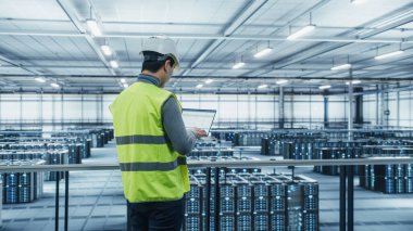 Yüksek Görüş Yelekli Veri Merkezi Mühendisi Laptop kullanıyor. Siber Güvenlik için Veri Koruma Ağı ile çalışan Asyalı Erkek Sistem Yöneticisi Sunucu Çiftliği Bulut Hesaplama Tesisi.