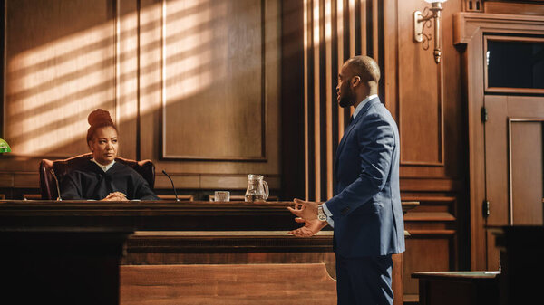 Судебный и судебный процесс: дело предстает перед судом мужского пола, выступает с речью перед судьёй, присяжными. Адвокат-афроамериканец защищает невиновных клиентов при помощи аргумента.