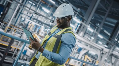 Yüksek Görüş Yelekli Afro-Amerikan Araba Fabrikası Mühendisi Tablet Bilgisayar kullanıyor. Otomotiv Endüstriyel Üretim Tesisi Otomatik Teknolojili Araç Üretimi. Hollanda Açı Vuruşu
