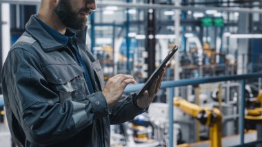 Otomotiv Endüstri Mühendisi Güvenlik Gözlüğü ve Üniforma Fabrikası 'nda Tablet Kullanımı. Modern elektrikli araçların imalatı üzerine çalışan Profesyonel Kurul Bitki Uzmanı.