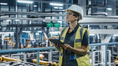 Yüksek Görüş Yelekli Kadın Araba Fabrikası Mühendisi Tablet Bilgisayar kullanıyor. Otomotiv Endüstriyel Üretim Tesisi Robot Teknolojisi ile Araç Üretimi üzerine çalışıyor. Otomatik Kurulum Tesisi.