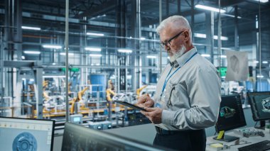 Otomatik Robot Silahlanma Hattı Üretim Hattı Yüksek Teknolojik Elektrikli Araçlar 'da Tablet Bilgisayar kullanan kıdemli Beyaz Erkek Mühendis Portresi. Yan Görünüm Görüntüsü