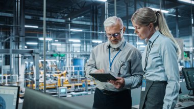 Otomobil Fabrikası: Kadın Proje Yöneticisi Erkek Otomotiv Mühendisi, Tablet Bilgisayar Planlama Stratejisi ile Görüştü. Otomatik Robot Silahları Toplama Hattı Üretim Üretim Elektrikli Araçlar