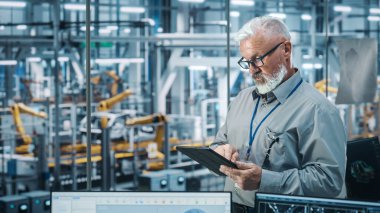 Otomatik Robot Silahlanma Hattı Üretim Hattı Yüksek Teknolojik Elektrikli Araçlar 'da Tablet Bilgisayar kullanan kıdemli Beyaz Erkek Mühendis Portresi. Orta Çekim