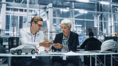 Araba fabrikasında çalışan iki genç otomotiv mühendisi. Endüstriyel Tasarımcı ve Meslektaşları Kişisel Hareket Aracında Metal Pinion Dişlilerinin Farklı Uygulamalarını Tartışıyor.