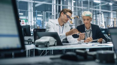 Araba fabrikasında çalışan iki genç otomotiv mühendisi. Endüstriyel Tasarımcı ve Meslektaşları Kişisel Hareket Aracında Metal Pinion Dişlilerinin Farklı Uygulamalarını Tartışıyor.