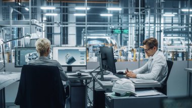 Otomotiv Mühendisleri Ekibi Modern Ofis 'teki Masaüstü Bilgisayarları üzerinde çalışıyor. Endüstriyel Ürün Tasarımcısı Araç Fabrikasındaki Meslektaşlarıyla Elektrik Motoru Parçaları Geliştiriyor.