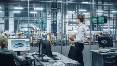 Gözlüklü ve Beyaz Gömlekli Yakışıklı Mühendis Tablet Bilgisayar kullanıyor ve bir araba montaj tesisinde ofisten dışarı bakıyor. Teknolojik Tesiste Araç Tasarımı üzerine çalışan Endüstriyel Uzman.