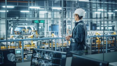 Üniformalı yakışıklı mühendis ve araba montaj tesisinde Tablet Bilgisayar kullanan. Endüstriyel Uzman Araç Tasarımı, Teknolojik Tesis Üretimi.