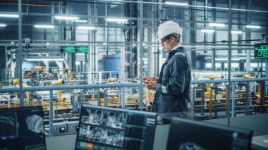 Üniformalı yakışıklı mühendis ve araba montaj tesisinde Tablet Bilgisayar kullanan. Endüstriyel Uzman Araç Tasarımı, Teknolojik Tesis Üretimi.