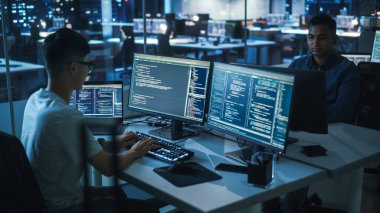 Gece Ofisi: Masaüstü Bilgisayarında Çalışan Genç Japon. Çeşitli Çoklu Etnik Programcılar Daktilo Kodu, Modern Yazılım Oluşturma, E-Ticaret Uygulama Tasarımı, E-İş Programı.