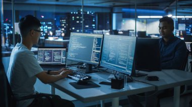Gece Ofisi: Masaüstü Bilgisayarında Çalışan Genç Japon. Çeşitli Çoklu Etnik Programcılar Daktilo Kodu, Modern Yazılım Oluşturma, E-Ticaret Uygulama Tasarımı, E-İş Programı.