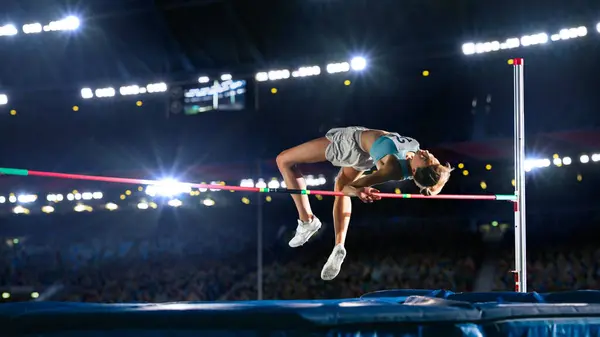 stock image High Jump Championship: Professional Female Athlete on World Championship Successfully Jumping over Bar. Shot of Competition on Stadium with Sports Achievement Experience. Determination of Champion.