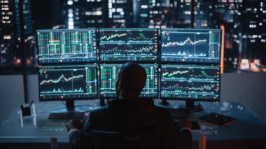 Borsa komisyoncusu, Multi-Monitor Workstation ve Real-time Yatırım, Emtialar ve Dış Döviz Çizelgeleri ile bir bilgisayar üzerinde çalışıyor. İşadamı Gece Ofisinde Veri Analizi Üzerinde Çalışıyor.
