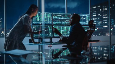 Finansal Analizci İş Gecesinde Yatırım Bankeriyle Konuşuyor. Multi-Monitor Workstation 'da Gerçek zamanlı hisse senedi verileri hakkında sohbet ediyoruz. İş adamlarının Komisyon Bürosunda toplantısı var.