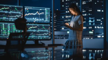 Finansal Analizci Tablet Bilgisayar Kullanıyor, Gerçek zamanlı borsa ve borsa grafikleriyle Çoklu Monitör Çalışma İstasyonunun yanında duruyor. Yatırım Bankası Şehir Ofisi 'nde çalışan iş kadını.