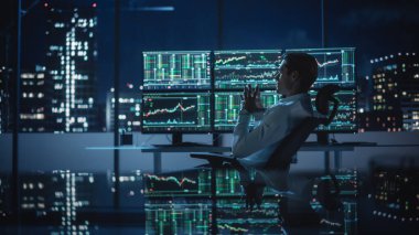 Finansal Analizci, Multi-Monitor Workstation ve Real-time Borsa ve Borsa Çizelgeleri ile bir bilgisayar üzerinde çalışıyor. İşadamı Yatırım Bankası Şehir Merkezi Ofisinde Gece Çalışıyor.