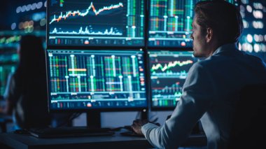 Finansal Analizci Multi-Monitor Workstation ve Real-time Stocks, Commodities ve Foreign Exchange Charts ile bir bilgisayar üzerinde çalışıyor. Yatırım Bankası Şehir Ofisinde Gece İşadamı Çalışıyor.