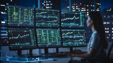 Finansal Analizci, Multi-Monitor Workstation ve Real-time Borsa ve Borsa Çizelgeleri ile bir bilgisayar üzerinde çalışıyor. Yatırım Komisyonculuğu Bürosu İş Kadınları Gecesi.