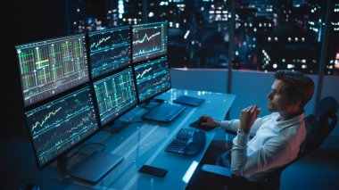 Finansal Analizci Multi-Monitor Workstation ve Real-time Stocks, Commodities ve Foreign Exchange Charts ile bir bilgisayar üzerinde çalışıyor. Yatırım Bankası Şehir Ofisinde İşadamı Gece Geç Saatlere Kadar Çalışıyor.