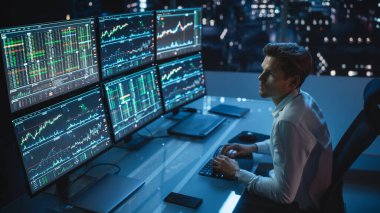Finansal Analizci Multi-Monitor Workstation ve Real-time Stocks, Commodities ve Foreign Exchange Charts ile bir bilgisayar üzerinde çalışıyor. Yatırım Bankası Şehir Ofisinde İşadamı Gece Geç Saatlere Kadar Çalışıyor.